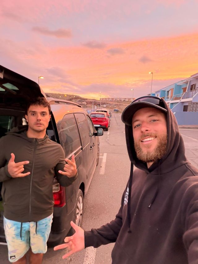 Dos riders junto a la furgoneta con un atardecer rosa al fondo
