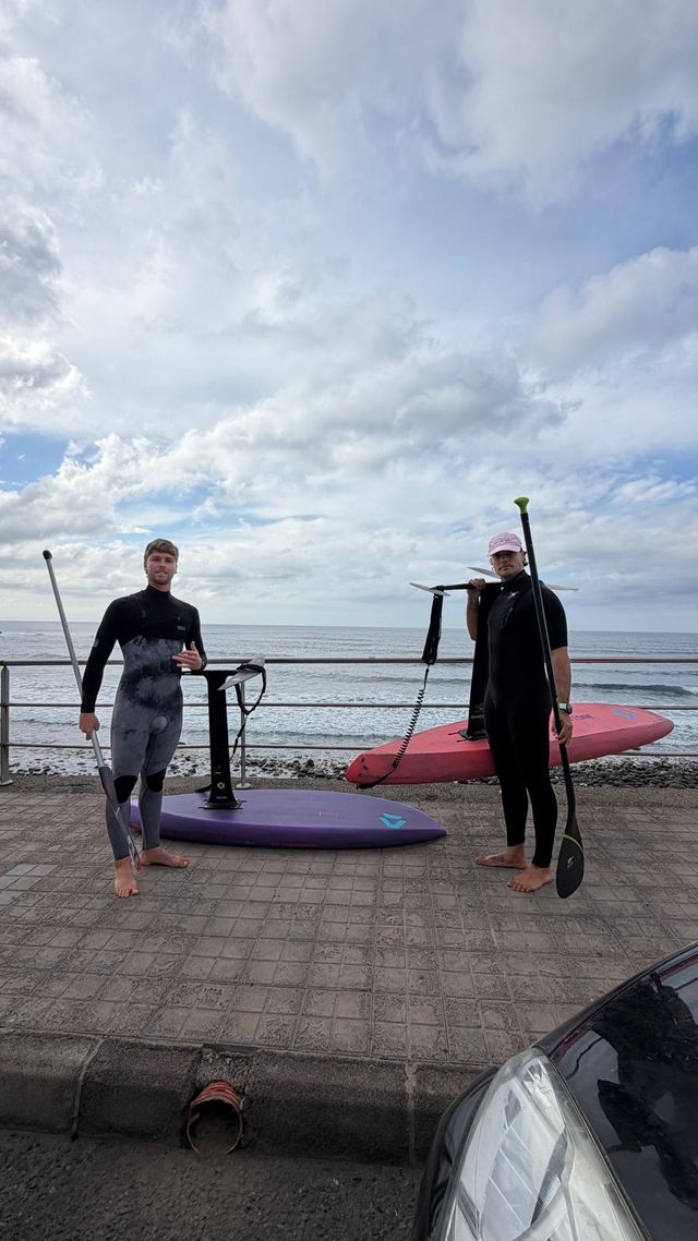 Dos riders con tablas de SUP foil y remos junto al mar